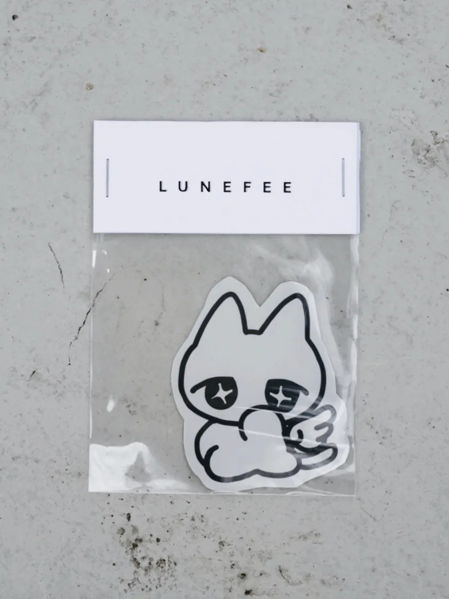 A Fee sticker in a clear bag with a Lunefee header card, on grey concrete